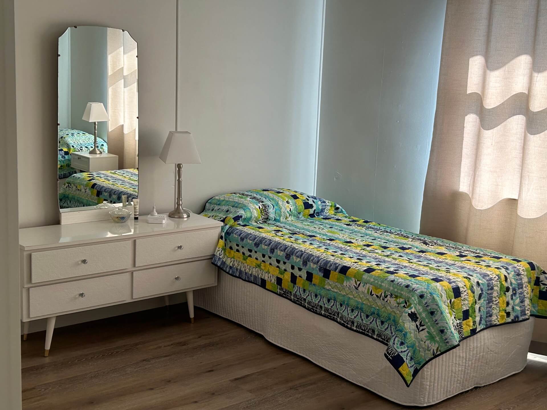 a bed with a colorful blanket next to a mirror