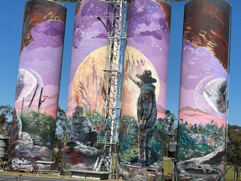 Monto's large silos with a painting of people and a moon